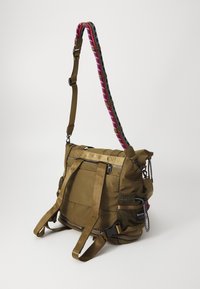 Bolso de hombro color verde oliva con una correa estampada, que presenta cremalleras, un bolsillo de malla y correas ajustables. Tejido duradero con acentos texturizados.