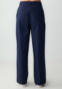 Pantalons larges bleu marine avec une taille élastique, fabriqués dans un tissu léger, présentant des coutures droites et des bords nets.