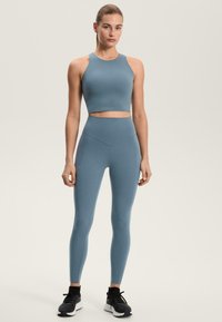 Modrý sportovní crop top a ladící legíny s vysokým pasem vyrobené z hladké, elastické látky s minimem švů a bez viditelných vzorů.