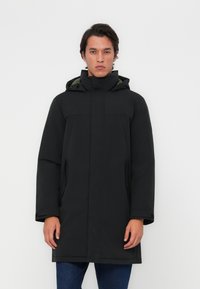 Zwarte parka met een capuchon, voorzien van een rits aan de voorkant, zijzakken en een gladde textuur. De binnenkant heeft een contrasterende groene voering.