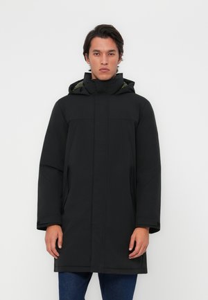 Parka negra con capucha, que cuenta con un cierre frontal, bolsillos laterales y una textura suave. El interior tiene un forro verde contrastante.