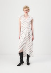 White dress with floral print featuring red cherries, short ruffled sleeves, a waist belt, and an asymmetric hem. Worn with knee-high black boots.