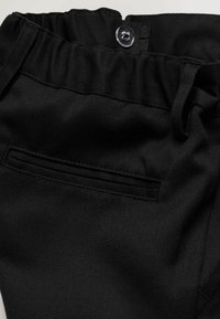 Schwarze Stoffhose mit elastischem Bund, Knopfverschluss, Gürtelschlaufen und einer horizontalen Gesäßtasche.