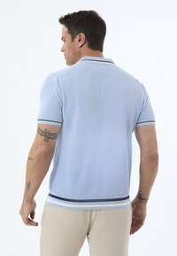 Ljust blå kortärmad pikétröja med strukturerad tyg, randig krage och nederkant. Har en slim fit och kontrasterande randiga detaljer.