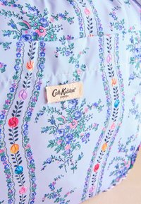 Tkanina torba s cvetnim vzorcem v svetlo modri barvi, ki vsebuje zelene in roza cvetove, z oznako Cath Kidston in dekorativnimi črtastimi detajli.