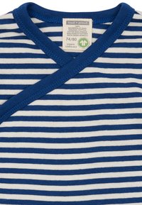 Top avvolgente a righe blu e bianche in cotone biologico con scollatura a coste. L'etichetta indica la taglia 74/80 e i dettagli di certificazione.