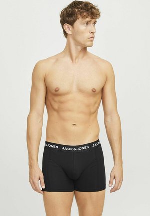 Boxer en coton noirs avec une ceinture logo blanche, design ajusté et longueur mi-cuisse, portés par un modèle.