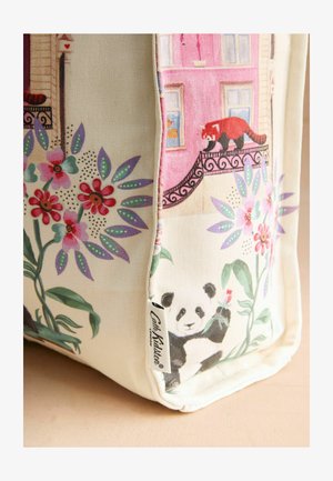 A sarok egy bézs színű szövet táskának, virágmintákkal, egy bambuszt tartó pandával, valamint egy vörös pandával egy erkélyen, rózsaszín ablakok alatt.