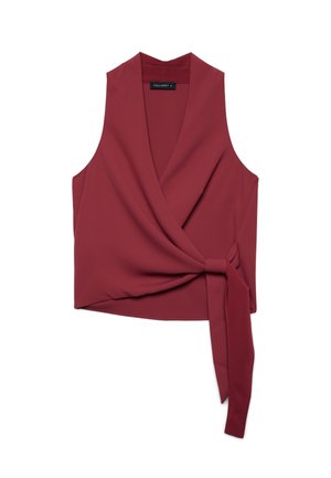 Blouse cache-cœur sans manches rouge profond avec col en V et détail de nœud latéral sur fond blanc.