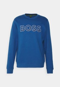 Blå sweatshirt i mjukt material, med rund halsringning, långa ärmar och stort vitt "BOSS"-logotyp över bröstet.