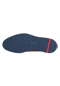 Rubberen zool met een blauwe gestructureerde oppervlakte met geometrische patronen, een rode accentstreep en logodetails aan de zijkant.