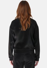 Felpa nera in satin con una vestibilità comoda, polsini e orlo a costine, che mostra una texture liscia e un design semplice sul retro.