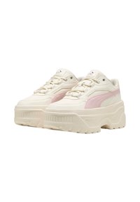 Sneaker color crema con suola spessa, caratteristiche dettagli in rosa, sovrapposizioni testurizzate e lacci rotondi. Logo PUMA sulla linguetta.