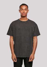 Black oversized T-shirt made of soft cotton with a round neckline, short sleeves, and clean stitching. Features a subtle faded texture.