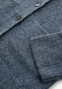 Grå ull cardigan med en texturerad yta, pryd med två svarta knappar, en v-ringning och ett ribbat manschettdetalj.