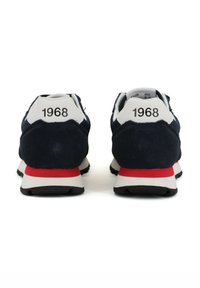 Marineblaue Nubuk-Sneaker mit weißen und roten Akzenten; mit "1968" geprägt an der Ferse, leichtem Gummisohle und klassischem sportlichem Design.