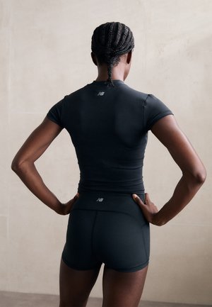 Camisa atlética negra de manga corta y diseño ajustado, acompañada de pantalones cortos ajustados a juego. Presenta un sutil logotipo en la parte posterior.