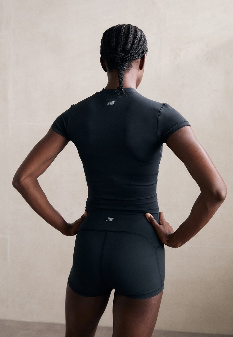 T-shirt de sport noir à manches courtes et design ajusté, associé à un short ajusté assorti. Présente un logo discret dans le dos.