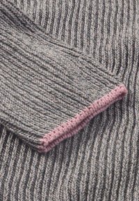 Grau gerippter Strickstoff mit einem kontrastierenden pinken Saum am Bündchen; die Textur ist weich mit sichtbaren Nähten und einem subtilen Glanz.