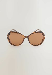 Lunettes de soleil en écaille de tortue avec montures octogonales, verres teintés marron et branches fines aux bords légèrement courbés.