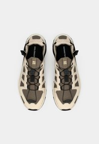 Paire de chaussures de sport Salomon beige et marron avec système de laçage rapide noir et dessus en tissu mesh, vue de dessus sur fond blanc.