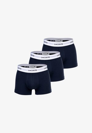 Navy blue cotton boxer shorts with elastic white waistband featuring the Lacoste logo. Three pairs displayed side by side.