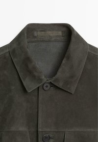 Giacca in pelle scamosciata verde oliva scuro con colletto appuntito e due bottoni neri visibili sul davanti.