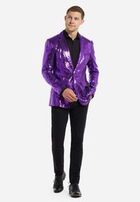 Violet blizginys su blizgiu paviršiumi, su piko apykaklėmis ir vieną mygtuką užsegamu dizainu, derinamas su juoda marškinėliais ir juodomis kelnėmis. Juodi elegantiški batai.