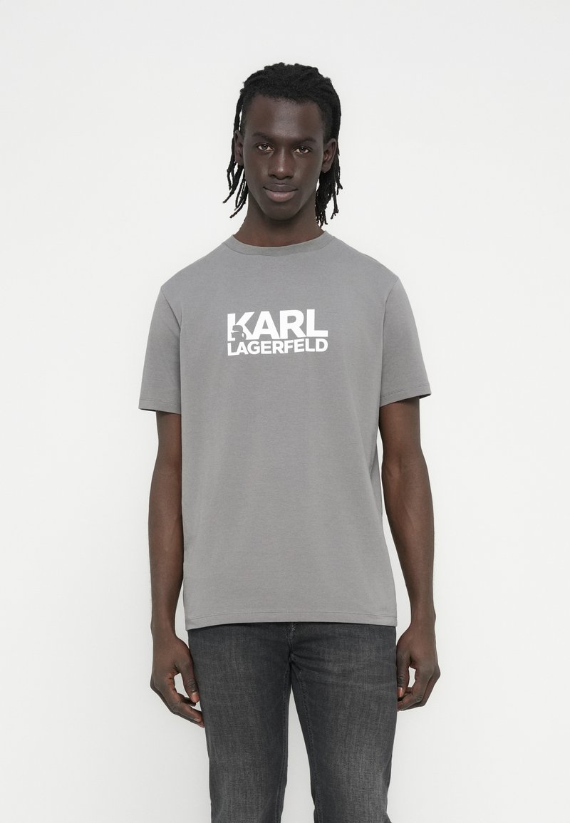 Szara bawełniana koszulka z krótkim rękawem, z białym nadrukiem logo "KARL LAGERFELD" na przodzie. Prosty, okrągły dekolt.