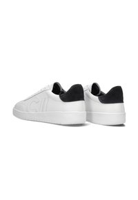 Witte leren sneakers met een gestructureerde zwarte suède accent op de hiel, platte veters en een rubberen zool, met verhoogde logo-details.