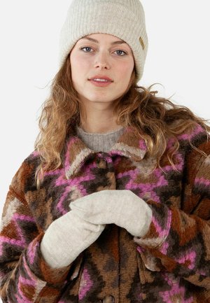 Kleurrijke wollen jas met een bruine basis en roze en paarse patronen. Gecombineerd met een lichtbeige gebreide muts en handschoenen.