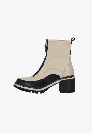 Botte en cuir beige et noir montante à la cheville avec talon épais, fermeture éclair frontale, semelle texturée et languette à l’arrière.