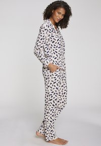 Lange mouwen pyjama set in crème met marineblauw abstract patroon. Bevat een knoopsluiting shirt en bijpassende broek met zijzakken. Zachte stof.