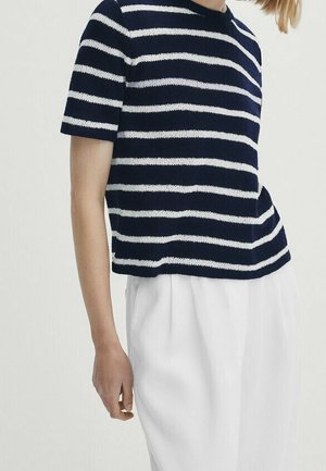 Navy blue and white striped knitted short-sleeve top with a round neckline, paired with white pleated trousers. The fabric appears soft.
