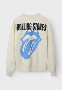 Cremfarbener Hoodie mit einem großen blauen Rolling Stones-Logo auf der Rückseite, mit schwarzem Text über dem Grafik. Weicher Stoff, lässige Passform.