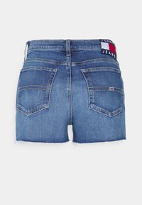 Shorts in denim di blu medio con orlo sfilacciato, due tasche posteriori e una toppa con logo che presenta accenti di colore rosso, bianco e blu sulla vita.