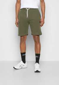 Bermuda in felpa verde oliva con vita elasticizzata, coulisse bianca, tasche laterali e una piccola etichetta logo sulla coscia.