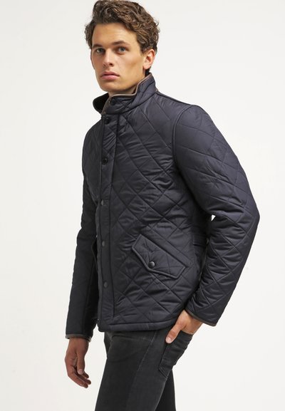 Veste matelassée bleu marine avec un col haut, des boutons-pression et des poches latérales. Présente un design texturé et rembourré pour le confort et le style.