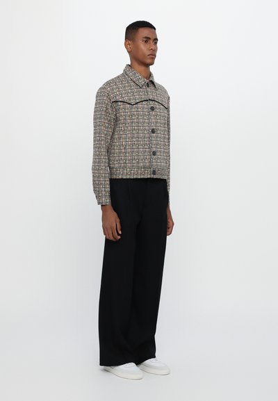 Checkered cropped jacket with long sleeves, button closure, and contrasting upper seam. Paired with wide black trousers and white sneakers.