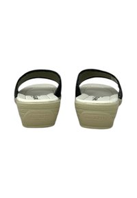 Sandali neri con cinturino, suola interna imbottita bianca, tacco rialzato, suola testurizzata e logo impresso sul lato esterno del tallone.