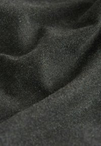 Tmavě šedá vlněná tkanina s viditelnou strukturou a záhyby, které ukazují jemné a mírně fuzzy povrchové detaily.