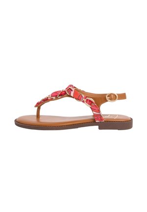 Hnedá plochá sandála s červeným vzorovaným pleteným látkovým remienkom a zlatou prackou na členku na bielom pozadí.