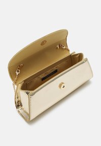 Clutch in pelle verniciata oro con tracolla a catena, dotato di chiusura a patta e superficie liscia e lucida. All'interno presenta slot per carte e branding.