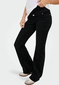 Black denim flared jeans with a mid-rise waist. Features front pockets, metal button accents, and a soft, stretchy texture.