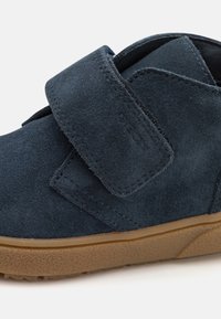 Granatowe zamszowe buty z rzepem, z wyściółką w podeszwie wykonaną z teksturowanej gumy oraz zaokrąglonym noskiem dla komfortu.