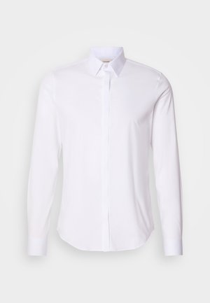 White long-sleeve shirt with a classic collar, button front, and smooth texture. Features a curved hemline and single button cuffs.