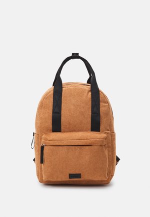 Petit sac à dos marron en velours côtelé avec poignées noires et poche avant zippée sur un fond gris clair.