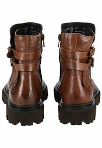 Botas de tobillo de cuero marrón con correas con hebillas, acabado texturizado, cremalleras laterales y suelas de goma negra gruesa. Presenta un acento de marca.