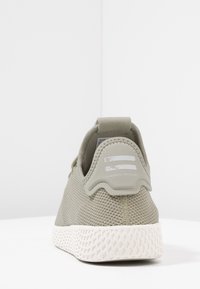 Světle zelené síťované tenisky s texturovaným povrchem, se bílou gumovou podrážkou a akcentem na zadní části paty se dvěma bílými pruhy a logem.