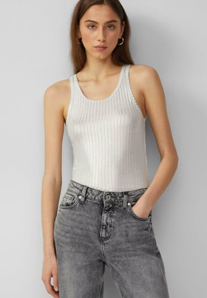 Zilveren mouwloze geribde tanktop met een ronde halslijn, gecombineerd met hooggerokte grijze denim jeans met een vervaagde afwerking.